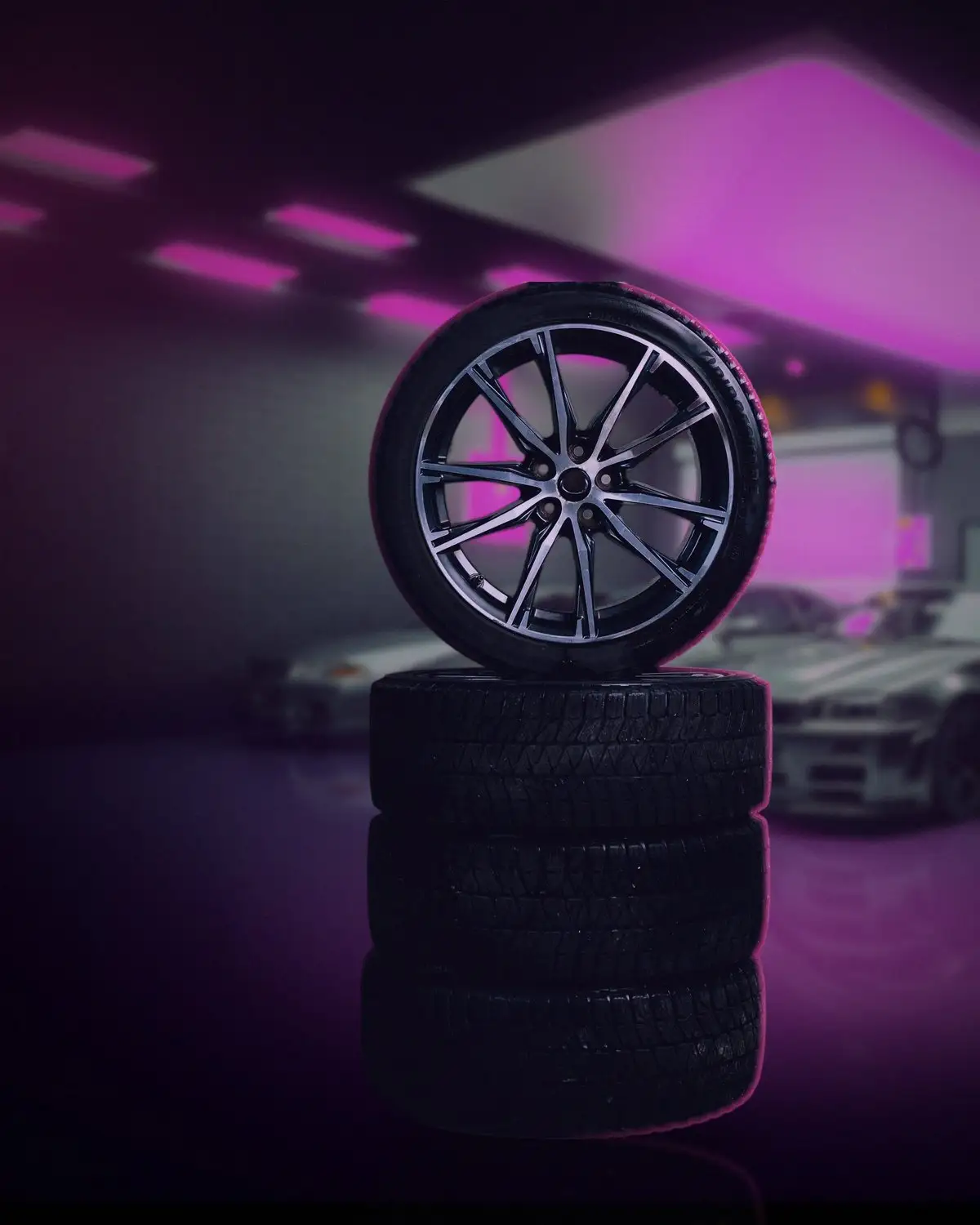 Four tyres stacked under pink neon light, the top one fitted to an alloy wheel.